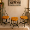Bring warmth and character to your home with this handcrafted 3-piece bistro set featuring two vintage-inspired iron chairs and a matching round table. Finished in a cheerful antique yellow with intricate hand-painted floral artwork, this eye-catching set combines traditional craftsmanship with timeless elegance, making it perfect for balconies, patios, cafés, gardens, and indoor spaces. Specifications Set Includes: 2 Chairs + 1 Round Table Material: Iron Finish: Antique Yellow with Hand-Painted Floral Design Color: Antique Yellow Style: Vintage / Bohemian / Rustic / Cottage Suitable For: Balcony, Patio, Garden, Café, Bistro, Indoor Seating Condition: Vintage